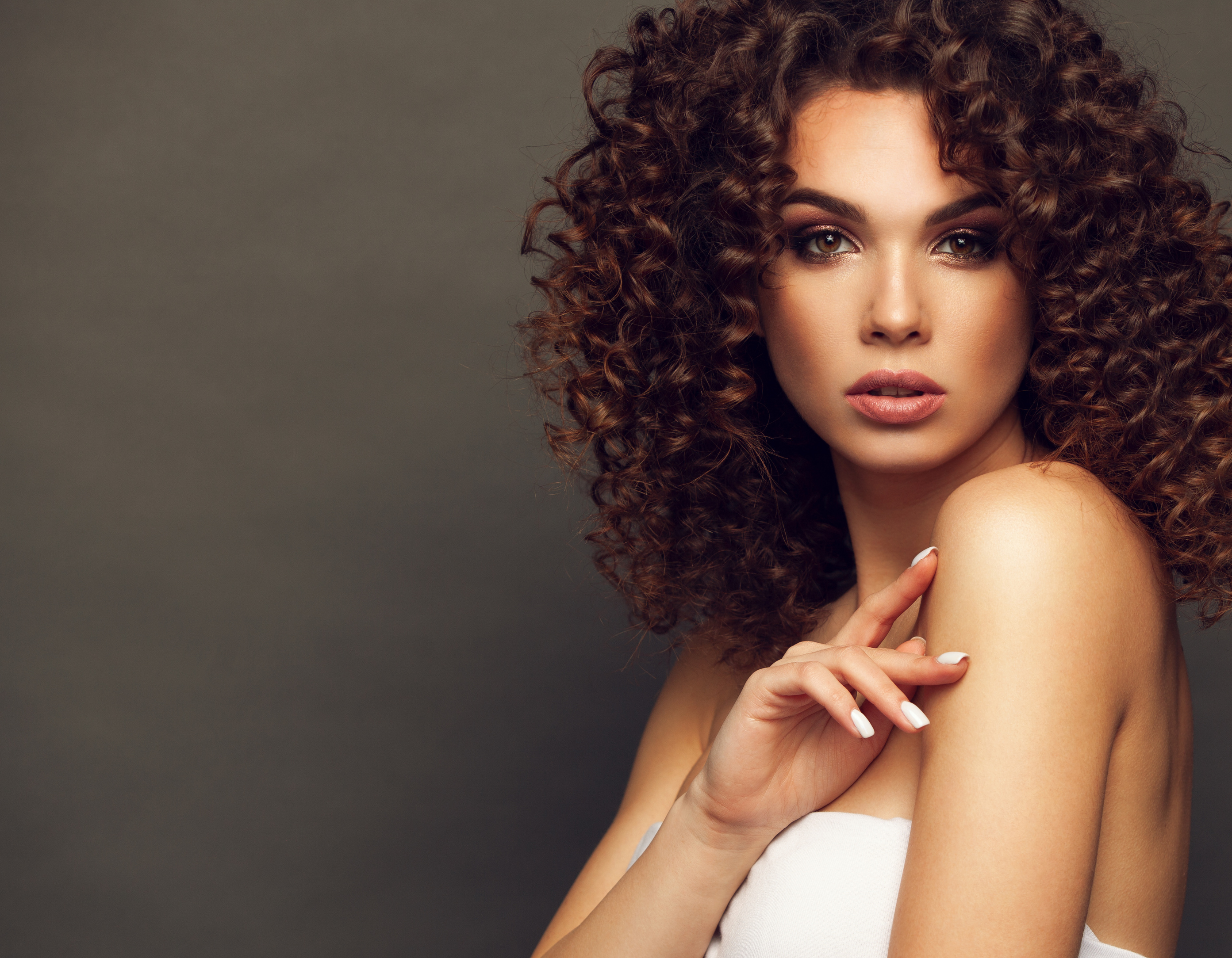 Fashion studio portrait of beautiful smiling woman with afro curls hairstyle. Fashion and beauty.